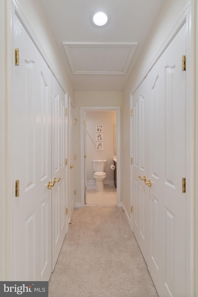 hall featuring light colored carpet and baseboards