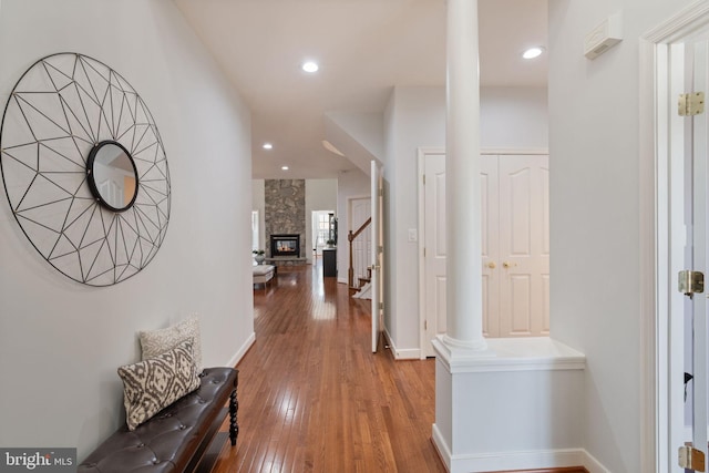 corridor with wood-type flooring, baseboards, stairway, recessed lighting, and ornate columns