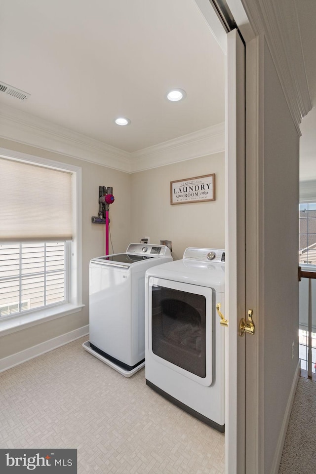 laundry area with crown molding, plenty of natural light, washing machine and dryer, and light colored carpet