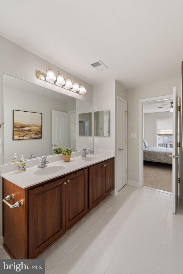 ensuite bathroom with connected bathroom, double vanity, visible vents, and a sink