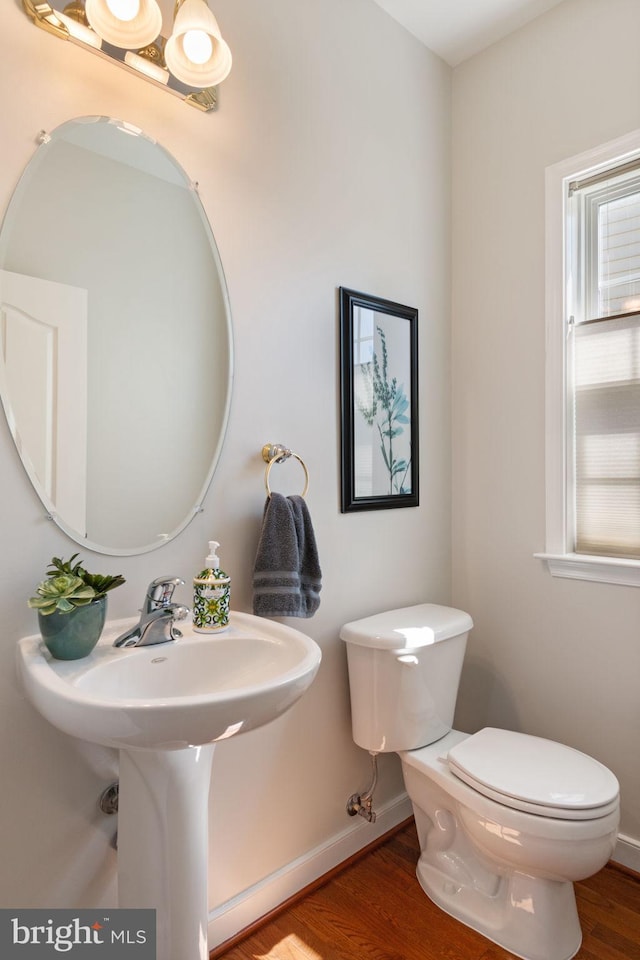 bathroom with toilet, baseboards, and wood finished floors