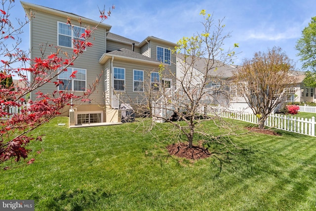 rear view of property featuring fence and a lawn