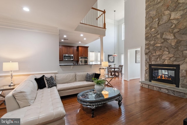 living room with crown molding, a towering ceiling, hardwood / wood-style floors, and a fireplace