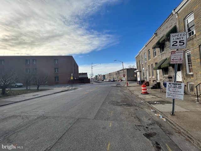 view of street with sidewalks, traffic signs, street lighting, and curbs
