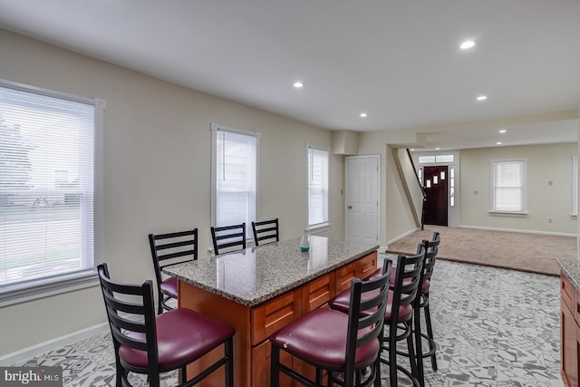 25 E High St, Felton, DE 19943 - kitchen with a kitchen bar, brown cabinets, recessed lighting, light stone counters, and a kitchen island
