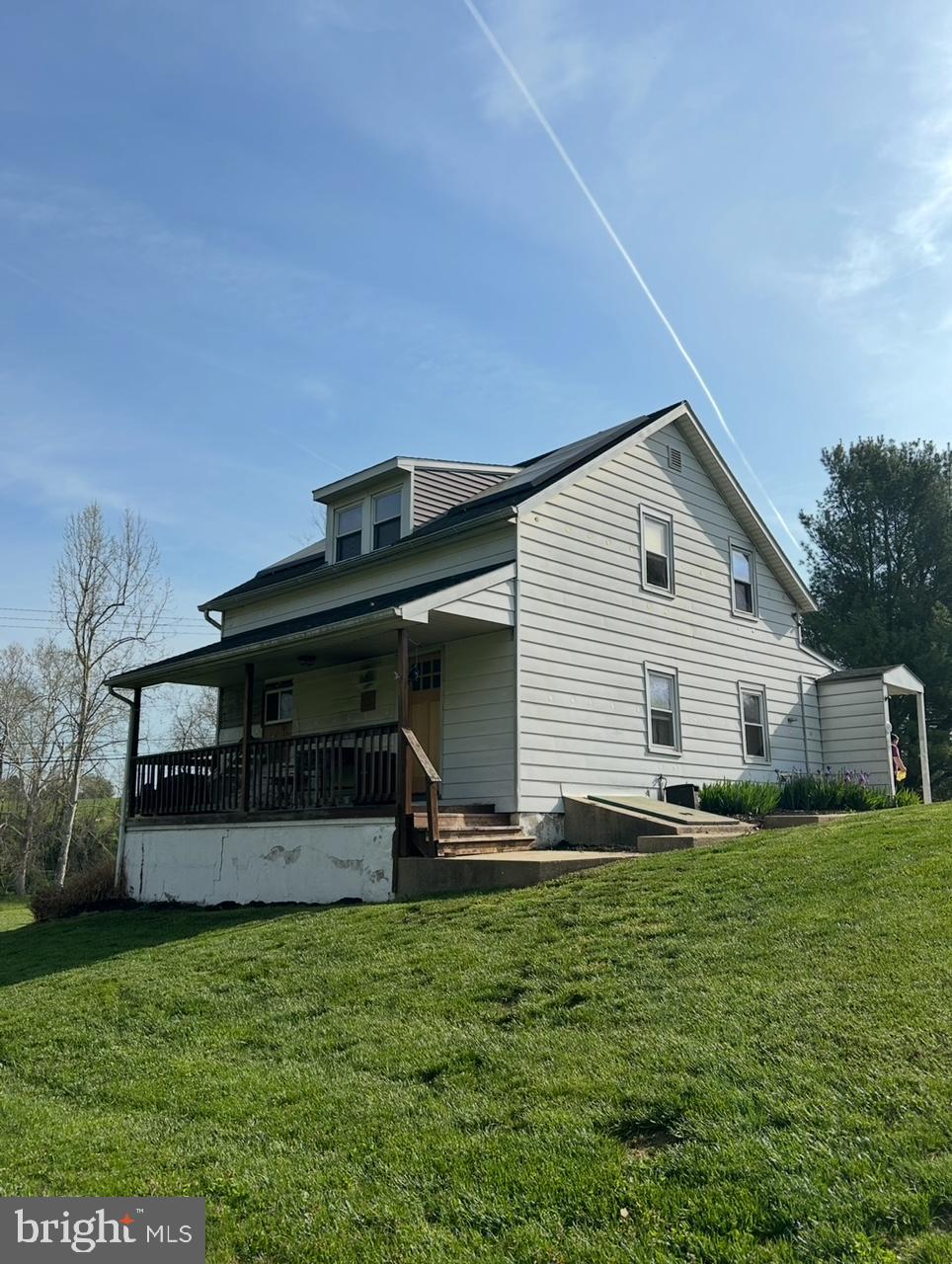 back of house with covered porch and a yard