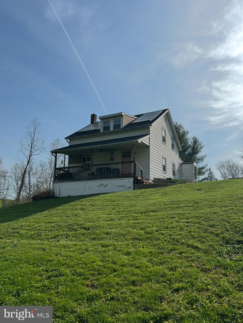 back of property featuring a porch, a yard, and a chimney