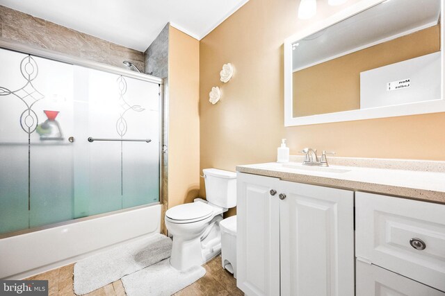 bathroom featuring vanity, enclosed tub / shower combo, and toilet