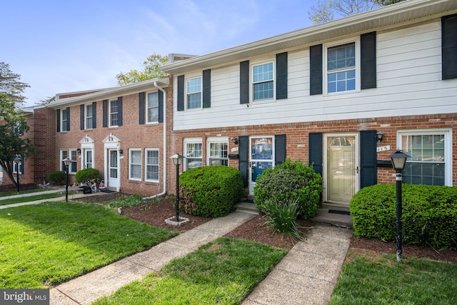 multi unit property with brick siding and a front yard