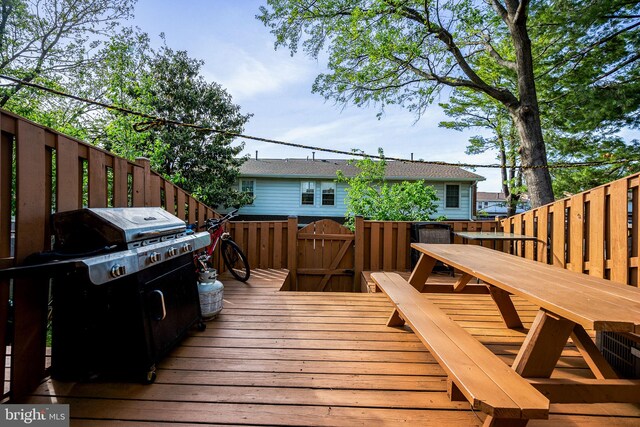 wooden deck with grilling area, outdoor dining area, and a fenced backyard