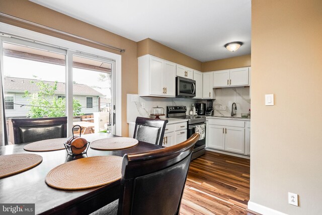 kitchen featuring stainless steel appliances, white cabinetry, a sink, and wood finished floors