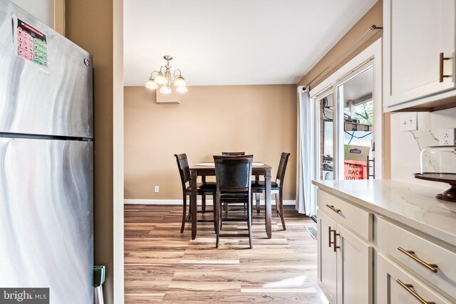 dining space with light wood-style floors, baseboards, and a notable chandelier