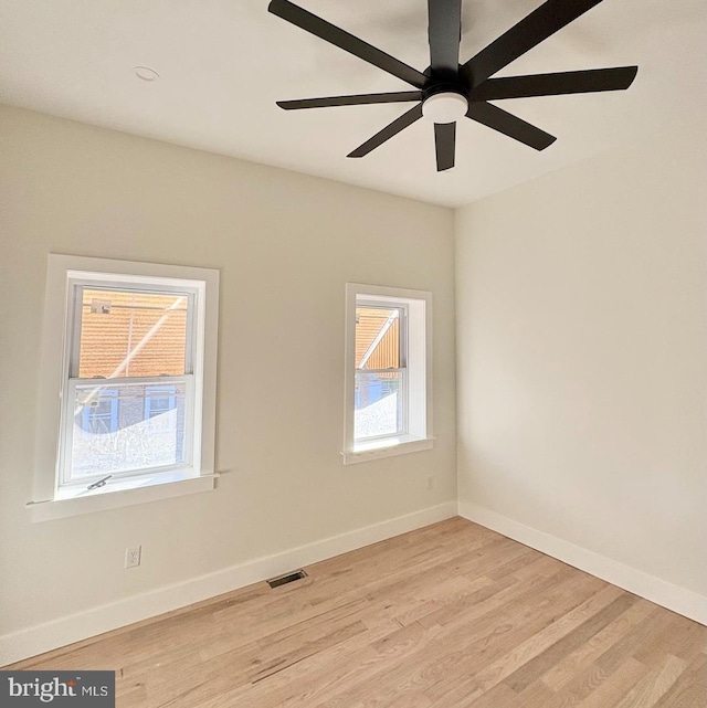 spare room featuring baseboards, ceiling fan, light wood-type flooring, and visible vents