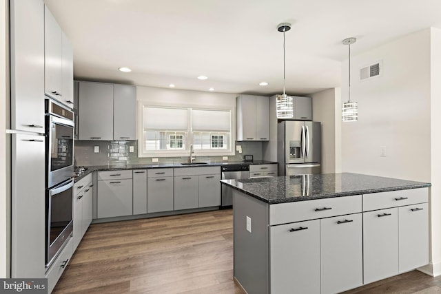 kitchen with backsplash, visible vents, a sink, stainless steel appliances, and light wood-style flooring