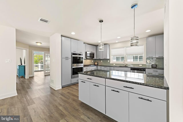 kitchen with decorative backsplash, visible vents, appliances with stainless steel finishes, dark wood finished floors, and a sink