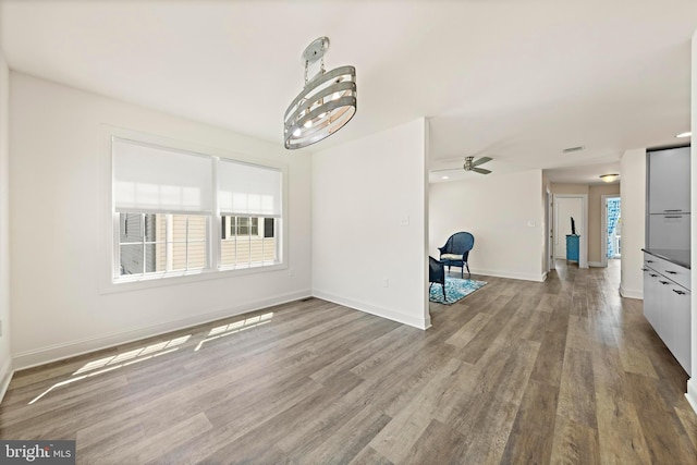 unfurnished dining area featuring a ceiling fan, baseboards, and wood finished floors