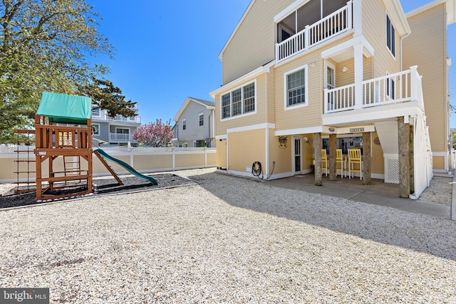 back of property with a playground and fence