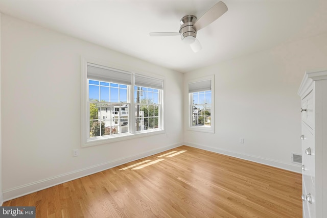 unfurnished room featuring visible vents, light wood-style flooring, ceiling fan, and baseboards