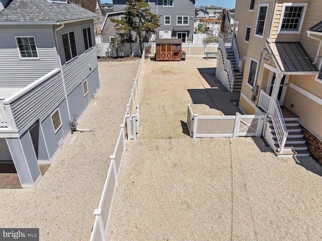 view of yard with a fenced backyard, an outbuilding, a residential view, and a storage shed