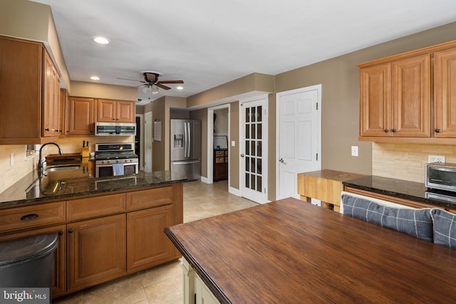kitchen featuring butcher block countertops, a sink, a ceiling fan, light tile patterned floors, and appliances with stainless steel finishes