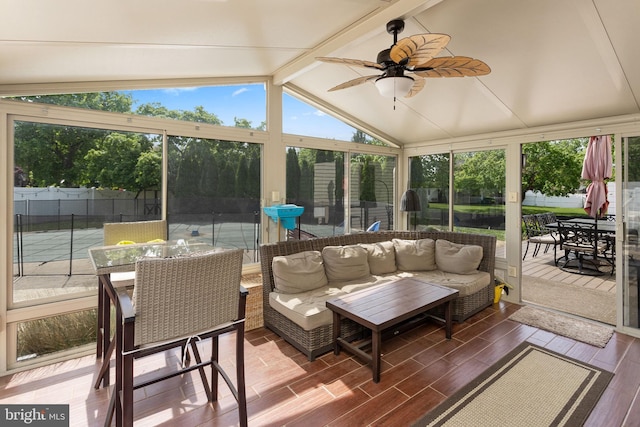 sunroom with ceiling fan, wood finished floors, outdoor dining space, and vaulted ceiling with beams