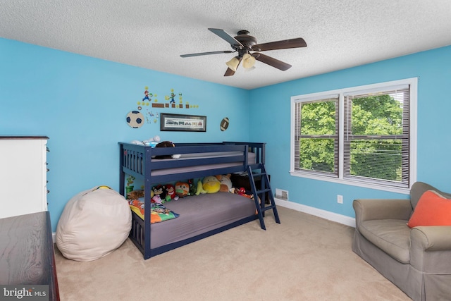 carpeted bedroom featuring a ceiling fan, baseboards, visible vents, and a textured ceiling