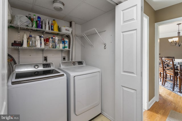 washroom featuring a notable chandelier, laundry area, light wood-style floors, and washer and clothes dryer