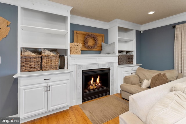 living room with a premium fireplace, light wood-style flooring, recessed lighting, a textured ceiling, and ornamental molding