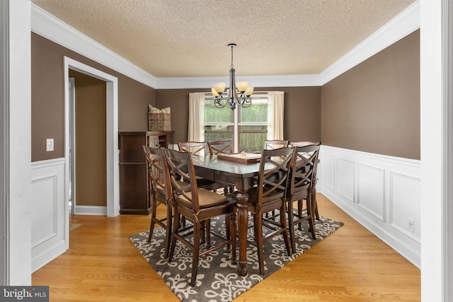 dining area featuring ornamental molding, a chandelier, and a textured ceiling