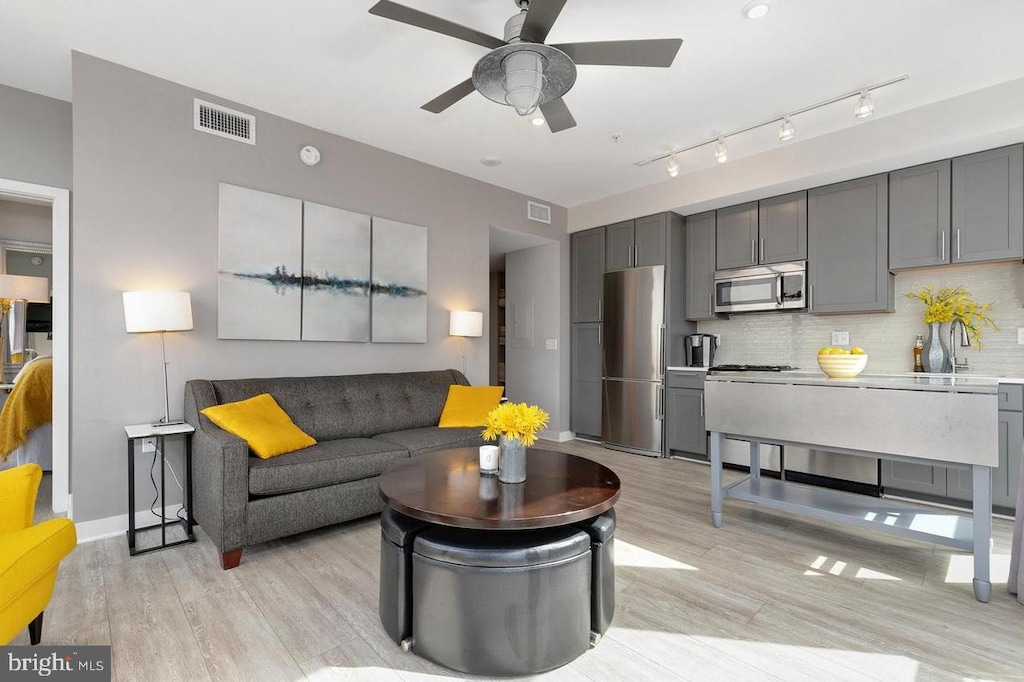 living area with ceiling fan, visible vents, and light wood-style flooring