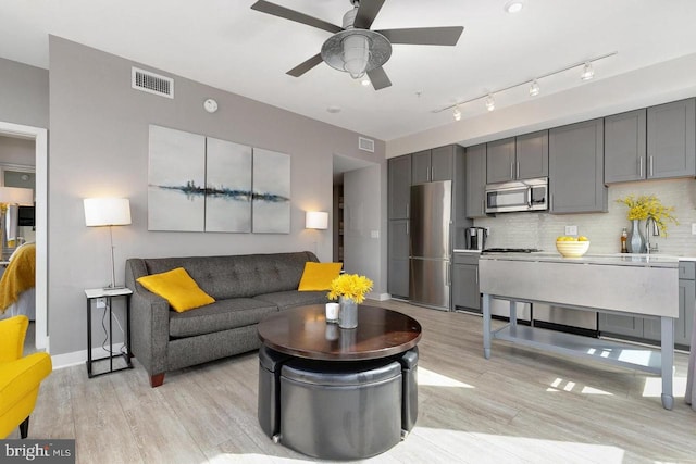 living area with ceiling fan, visible vents, and light wood-style flooring