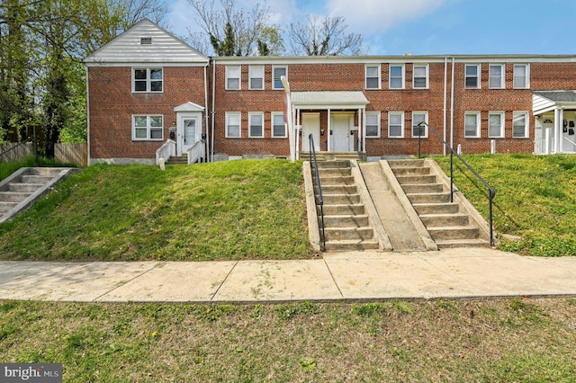 view of front facade featuring brick siding, stairs, a front yard, and entry steps