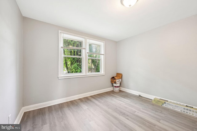spare room with baseboards and wood finished floors