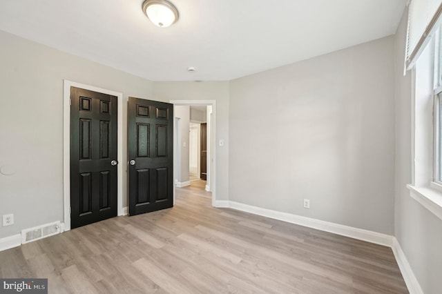 unfurnished bedroom featuring baseboards, visible vents, and light wood-type flooring