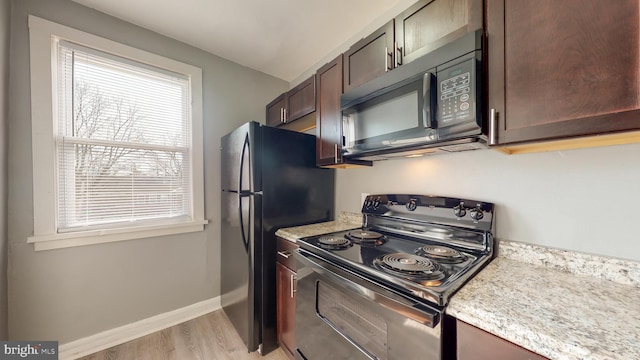 kitchen featuring dark brown cabinets, baseboards, light wood-style flooring, and black appliances