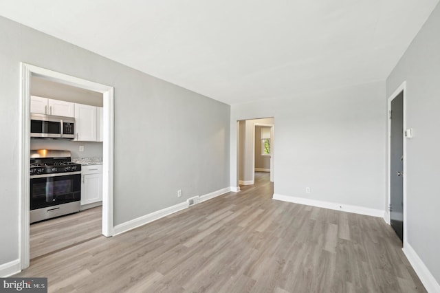 unfurnished living room featuring baseboards, light wood-style flooring, and visible vents