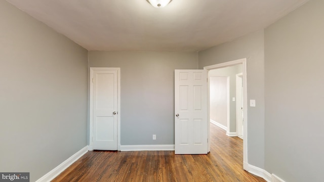 unfurnished bedroom featuring baseboards and dark wood finished floors