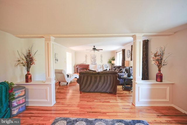 living room featuring ceiling fan, decorative columns, and light wood finished floors
