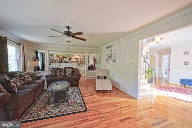 living room with crown molding, visible vents, ceiling fan, stairway, and light wood-type flooring