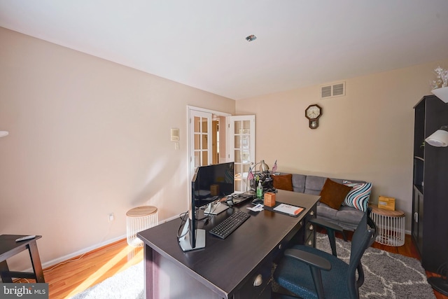 home office featuring baseboards, french doors, wood finished floors, and visible vents