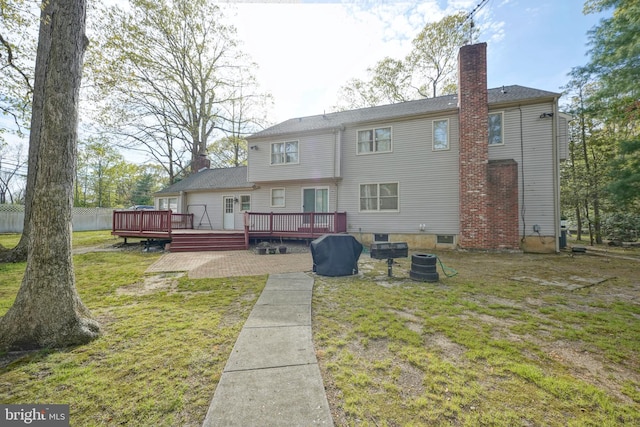 back of property with a yard, a deck, central AC, and a chimney