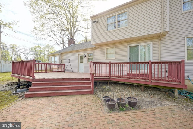 rear view of property featuring a patio area, a wooden deck, and a chimney
