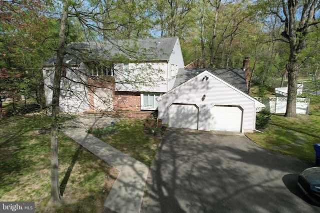 view of side of property featuring a garage, aphalt driveway, roof with shingles, a chimney, and brick siding