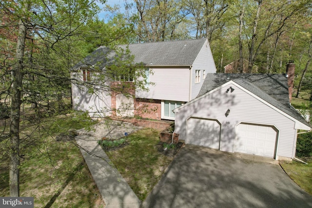 view of property exterior featuring a garage, a chimney, brick siding, a shingled roof, and driveway