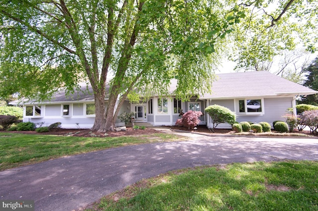ranch-style house featuring aphalt driveway and a front lawn