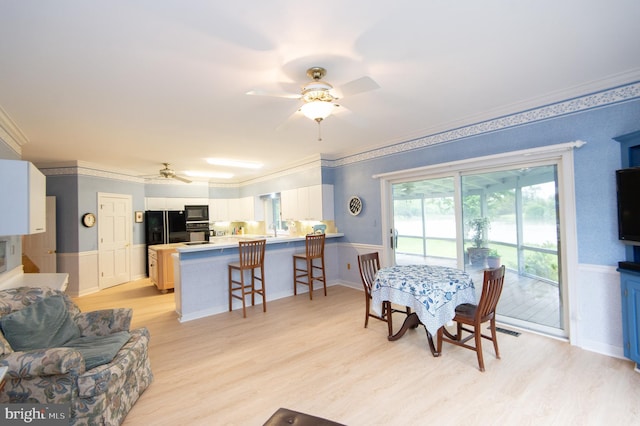2210 Horns Point Rd, Cambridge, MD 21613 - dining area featuring ceiling fan, a wainscoted wall, light wood-style floors, and ornamental molding