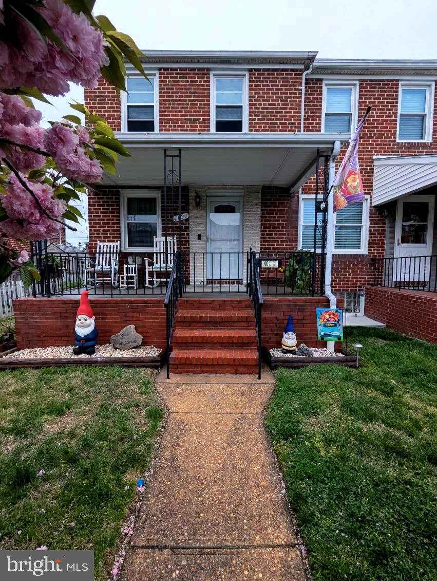 view of front of house featuring a front yard, a porch, and brick siding