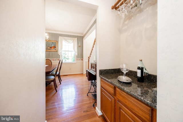 interior space with baseboards, a dry bar, and light wood finished floors