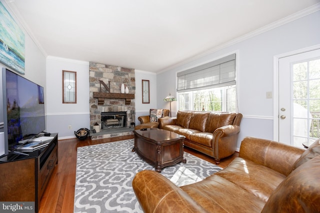 living room with baseboards, ornamental molding, wood finished floors, and a fireplace