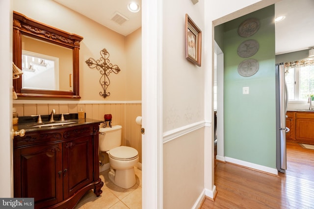 bathroom with vanity, toilet, wood finished floors, and visible vents